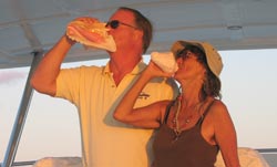 Captain Tom and Alicia blow queen conch shells at sundown in the Caribbean aboard Tom's boat.